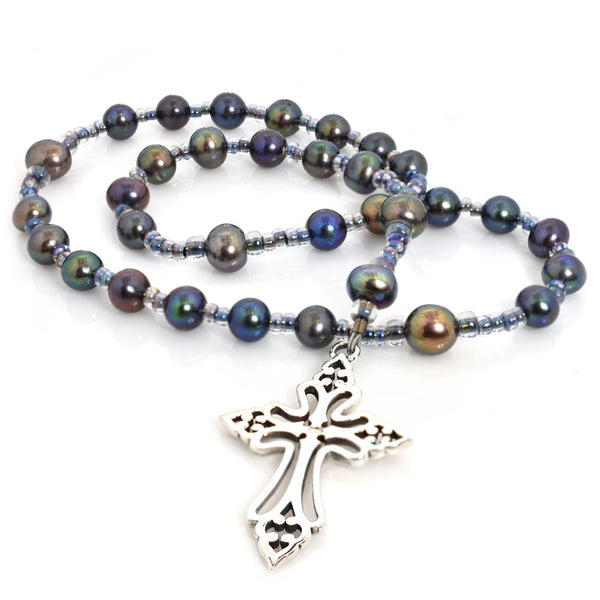 A string of round beads, featuring blue pearls, with a silver Celtic Clechee cross pendant at the center.