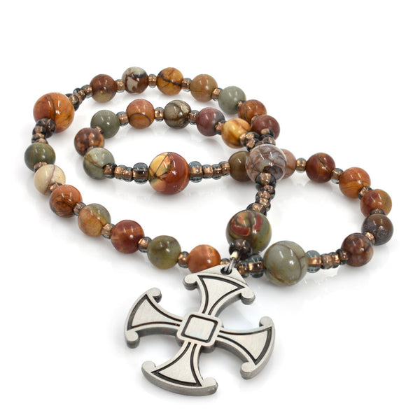 A string of round, red creek jasper beads, with a silver Canterbury Cross pendant at the center.