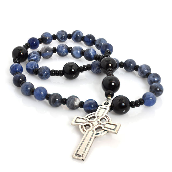 A string of round beads, featuring sodalite and onyx, with a silver Celtic Aura cross pendant at the center.